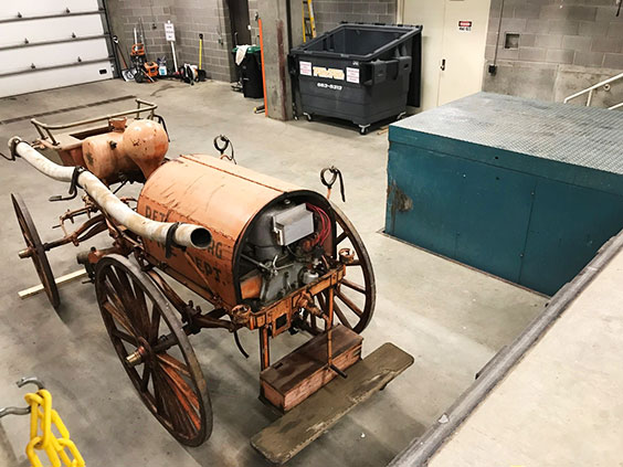 Antique fire wagon in a garage in front of a raised platform