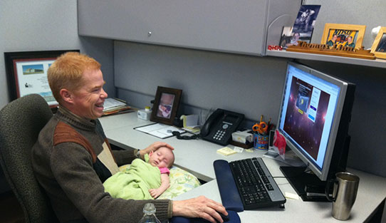 Employee at his work desk with baby daughter