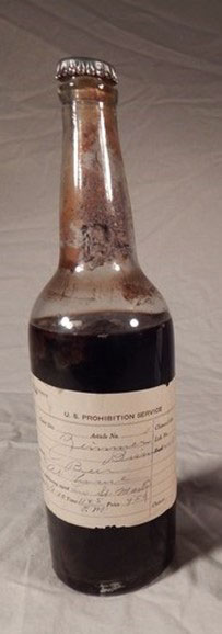Mostly full beer bottle with evidence label from the U.S. Prohibition Service