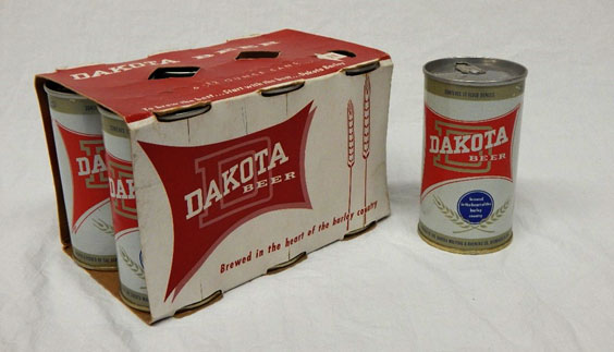 Dakota Beer 6 pack and can. The logo is white text on an odd 4 corner shape. There is a gold D behind the text. There are also a couple wheat stocks.
