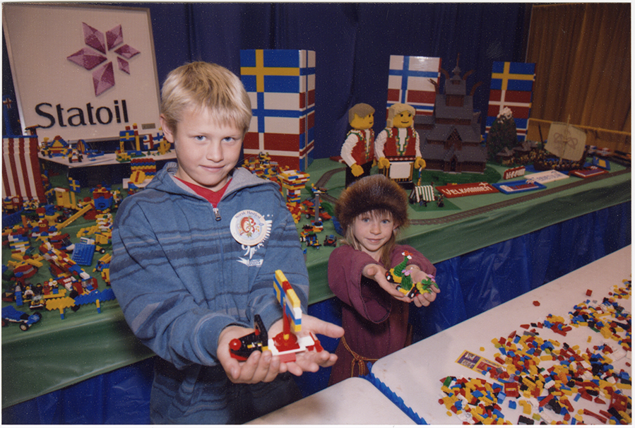 Children show off their creations, 2013. An elaborate Scandinavian LEGO display is visible in the background. SHSND SA 11762
