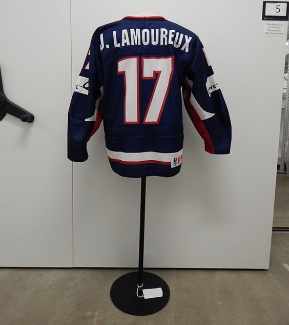 The back of a jersey that's navy blue with a thick white band and thinner red band around the bottom of the jersey. The arms have white patches on them towards the middle. J. Lamoureux is listed in white at the top of the jersey, and 17 is listed under it in large white lettering outlined in red.