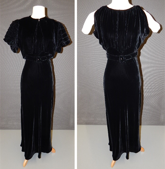 Two side by side images of a black felvet dress. The first image has a matching short sleeved coat over the top of it. It is a full-length, sleeveless dress that is somewhat form fitting with a matching belt around the waist.