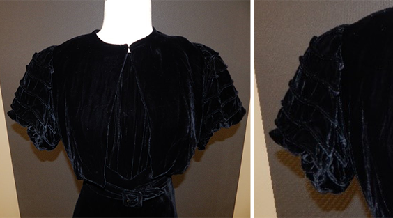 A black velvet jacket that clips together at the neck with short sleeves that are puffed.