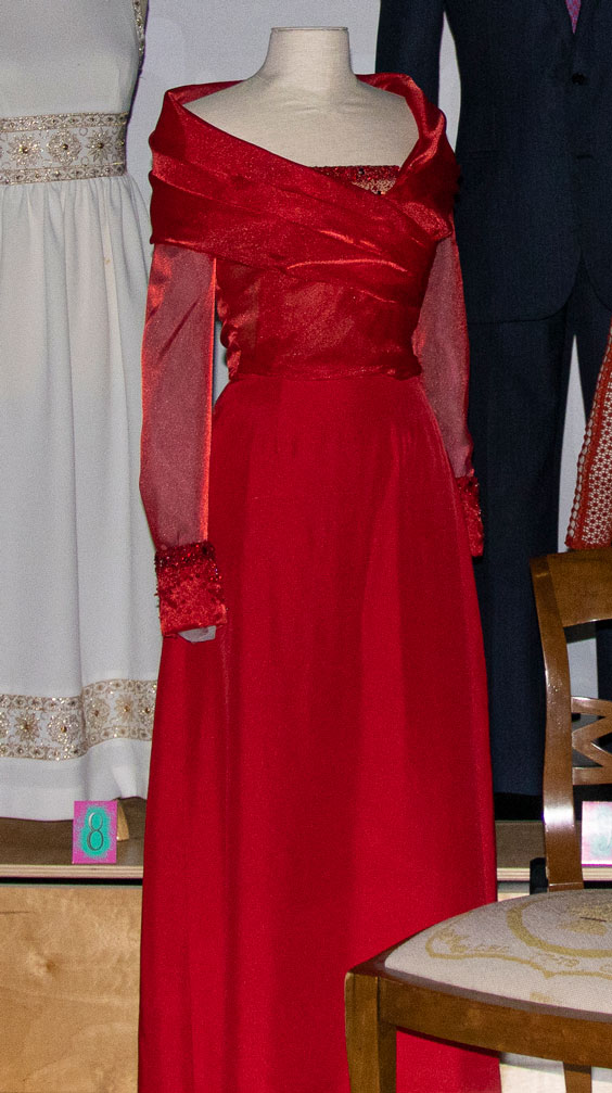 A long, red dress with sleeves that is being displayed on a mannequin