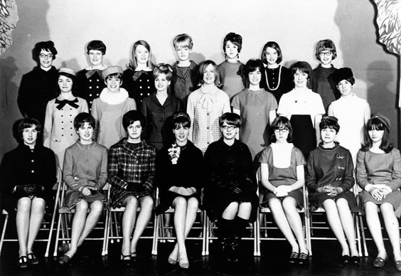 Three rows of women with the front row seated show off the dresses they made for the Make it Yourself with Wool contest.