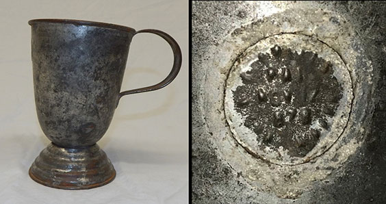 A tarnished looking dark colored cup and a close up detail of a marking on it that looks like seeds