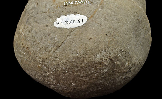 A large rock with a battered end is shown. There is a spot of white paint on it with 15312-A written in black ink on the white paint.