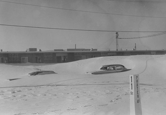 Two cars are shown buried in a snow drift.