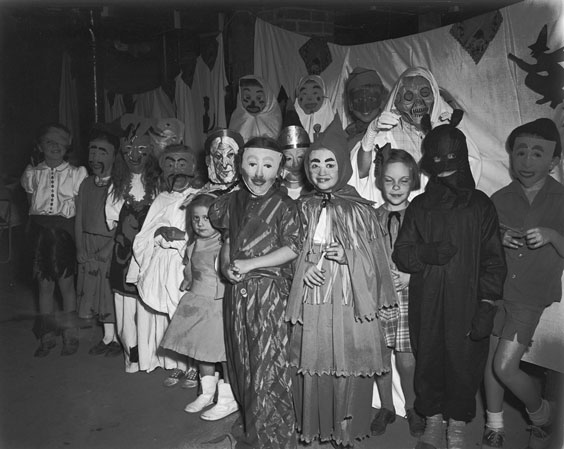 many children and a few adults are dressed up in Halloween masks