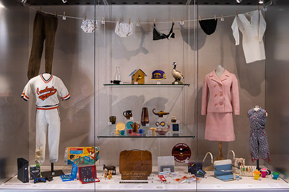 A small exhibit with underwear hanging on a clothes line and many other small objects on the floor of the case