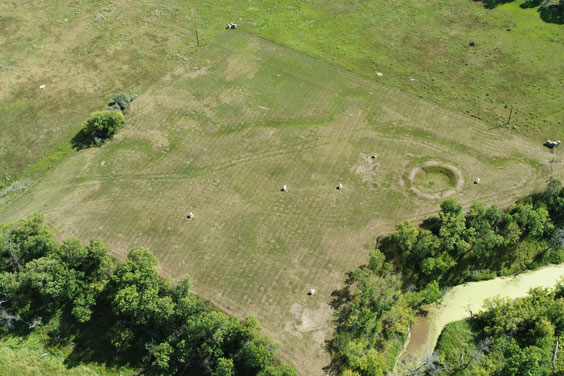 An aerial view of a patch of land where the outline of a ditch surrounding the area can be seen