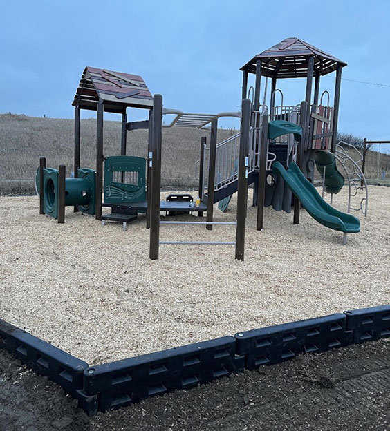 Playground equipment with green slides and brown poles and roofs