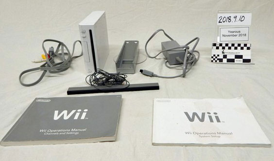 A Nintendo Wii with its cords, sensor, and operations manuals