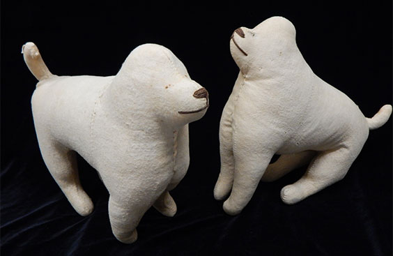 Two cream colored dog stuffed animals with very short tail