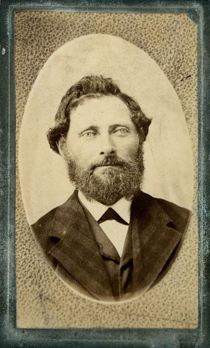 portrait of a man with a beard and mustache who is wearing a button up shirt, vest, and jacket.