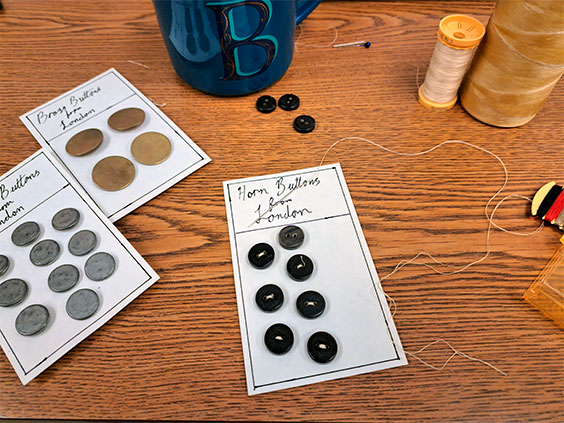 Three different sets of buttons are shown sewn onto three separate pieces of paper.