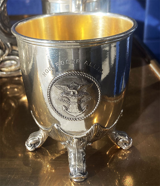 USS North Dakota Silver Service punch cup. The emblem on the cup is of an eagle sitting on top of a bundle of wheat with an anchor coming out the bottom and a ship wheel behind the eagle.