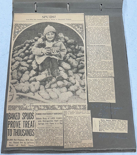 Newspaper article with an image of a little girl sitting on a pile of potatoes. The headline of the article is Baked spuds prove treat to thousands.