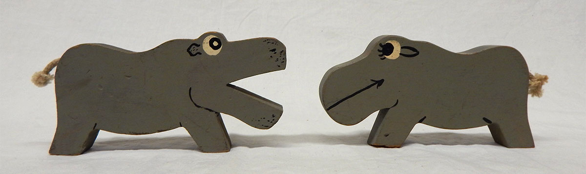 A set of wooden male and female hippos with rope tails.