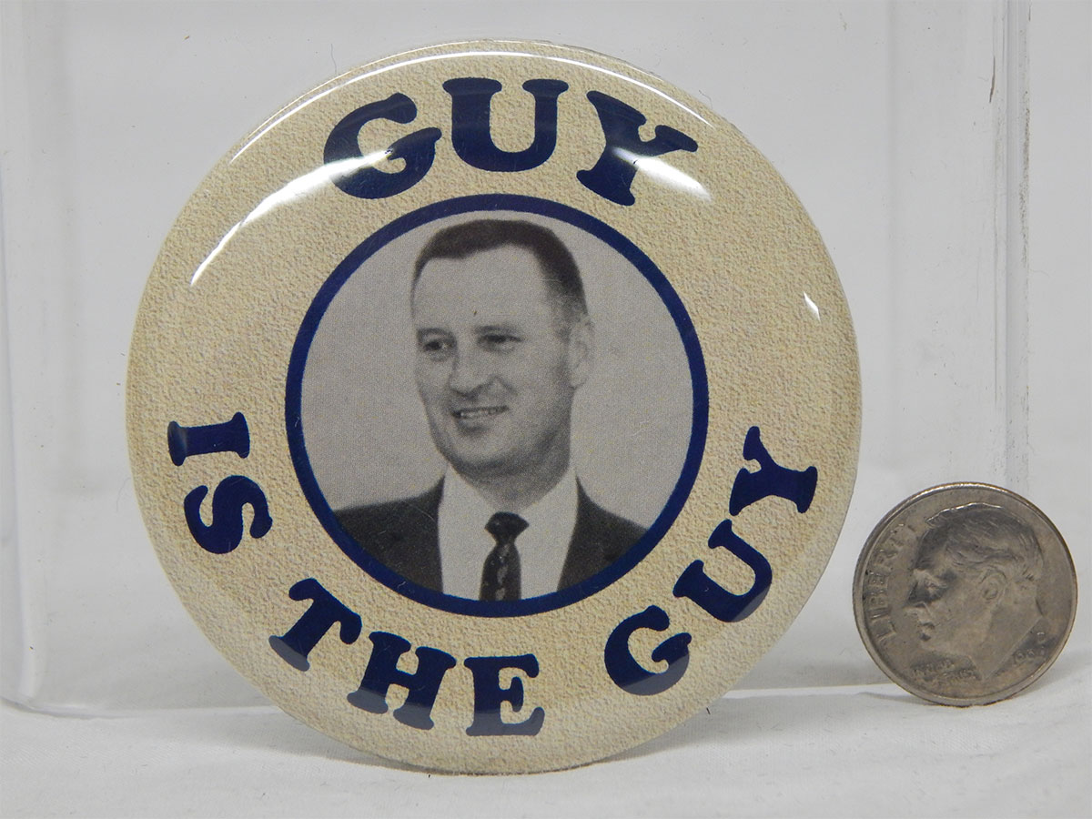 A pin that reads GUY IS THE GUY with a picture of a man in a suit and tie in the middle.