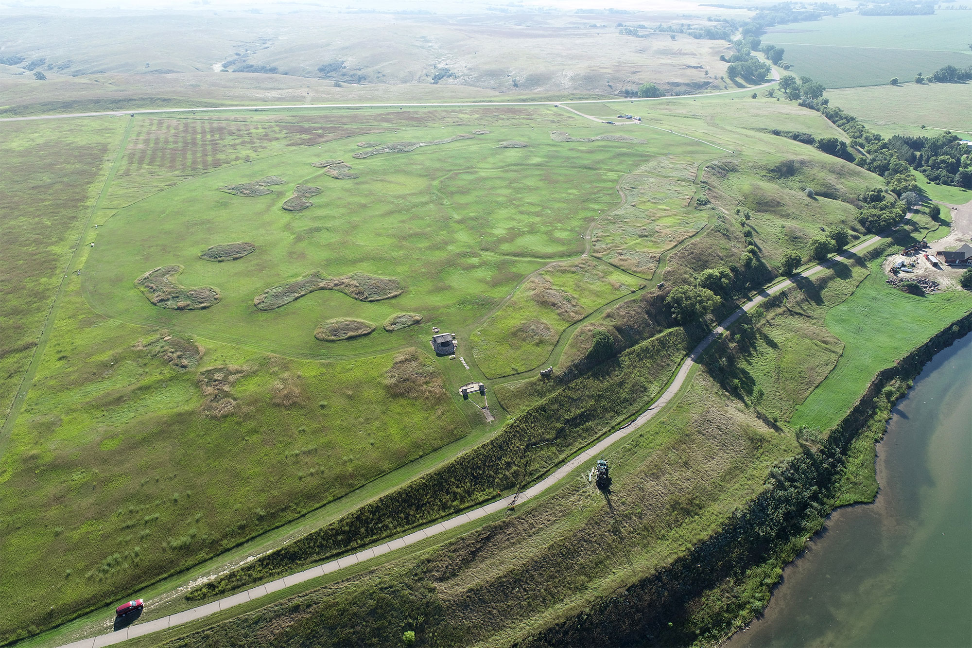 Fortification ditches, earthlodge depressions, midden mounds, and the walking trail present at Double Ditch Indian Village State Historic Site are visible in this image captured by an uncrewed aerial vehicle