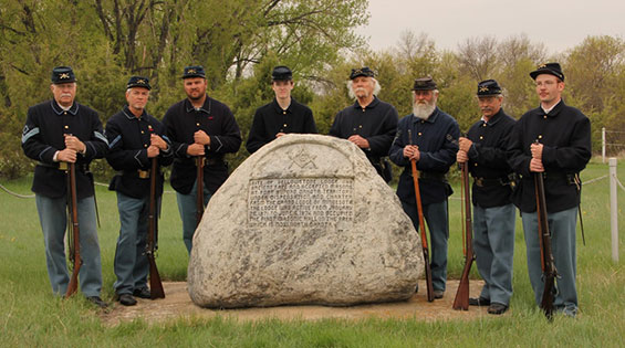 6th Infantry reinactors wearing time period hats, jackets, and pants and holding muskets