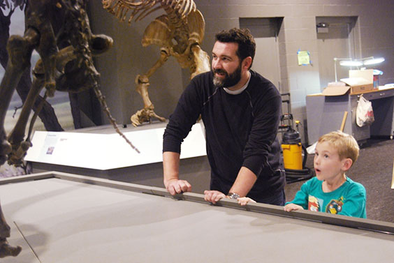 Bryan and young museum visitor smiling at dino bones