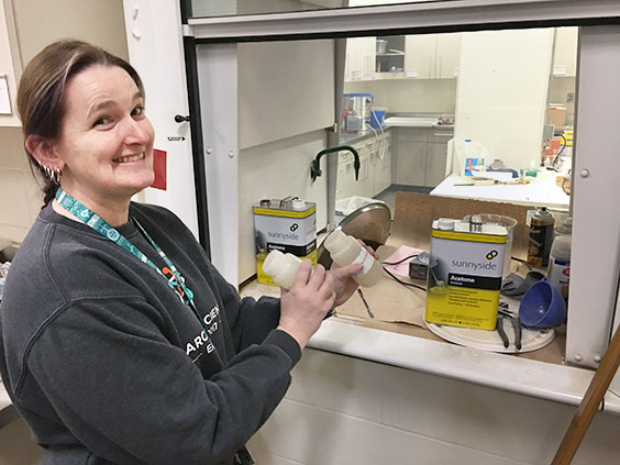 Becky holdling two small bottles and smiling at the camera