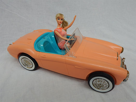 orange barbie car with vintage barbie sitting in drivers seat