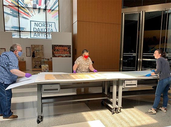 museum staff unrolling large mural piece