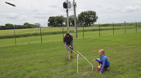 Two people shooting off foam rockets from PVC pipe launcher