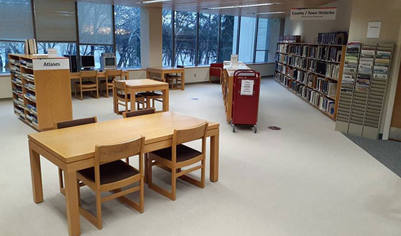 A red card on wheels is shown in the middle of wooden tables and chairs and bookcases filled with books.
