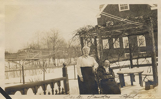 Catherine Weldon and another lady outside with a house and trees in the background