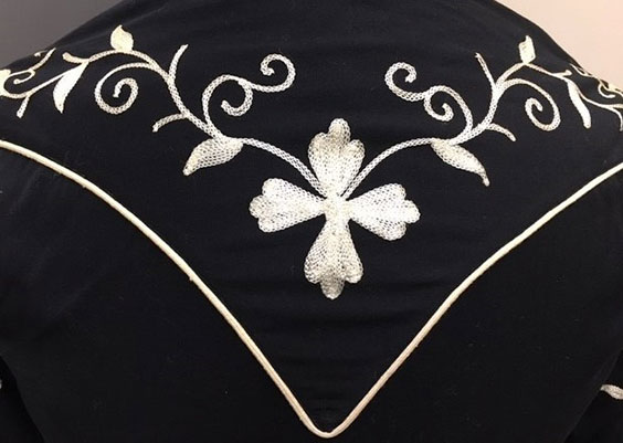 White line in a v shape with white embroidered flowers, vines, and leaves on a black shirt