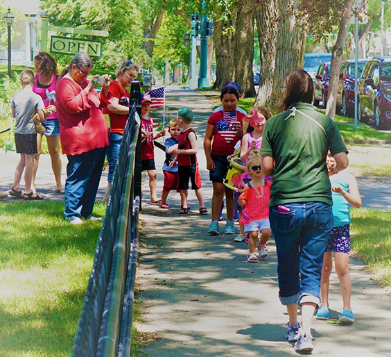 Kris leading a parade of children with others spectating