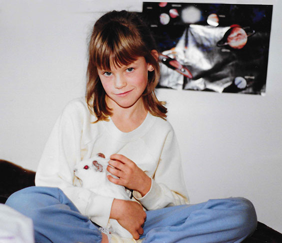 Jessica holding a guinea pig with a space poster in the background