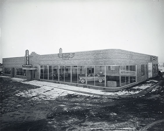 Exterior of Chrysler dealershp with a car visible through the window