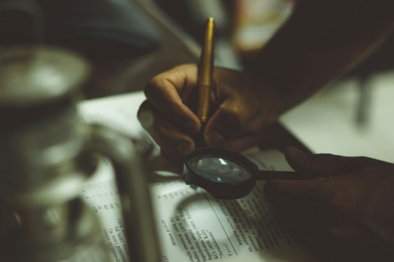 Reading and writing in a book with a magnifying glass and pen