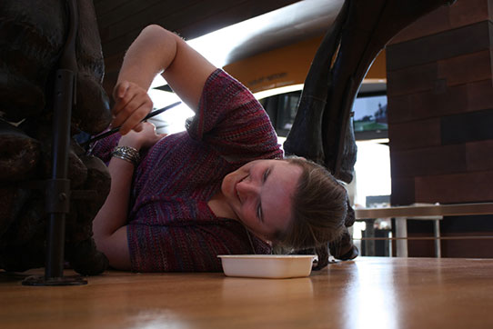 Becky Barnes lying down to paint the mastodon repair.