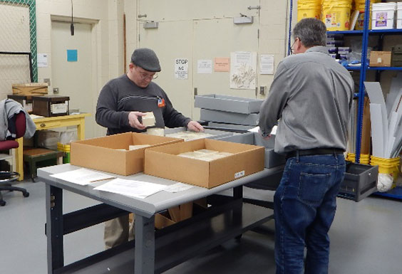 student and teacher moving boxed eggs