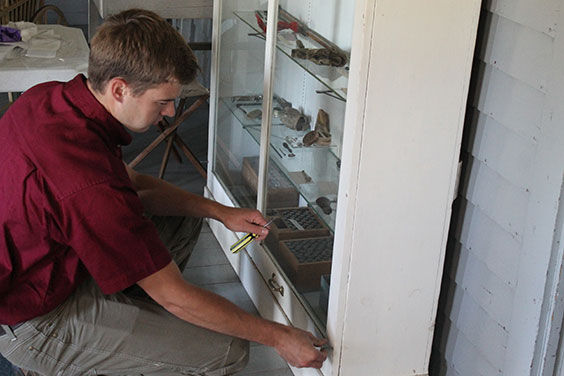 Young gentleman holding a screwdriver and working on an exhibit case