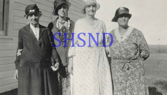 Old picture of four ladies in dresses and hats